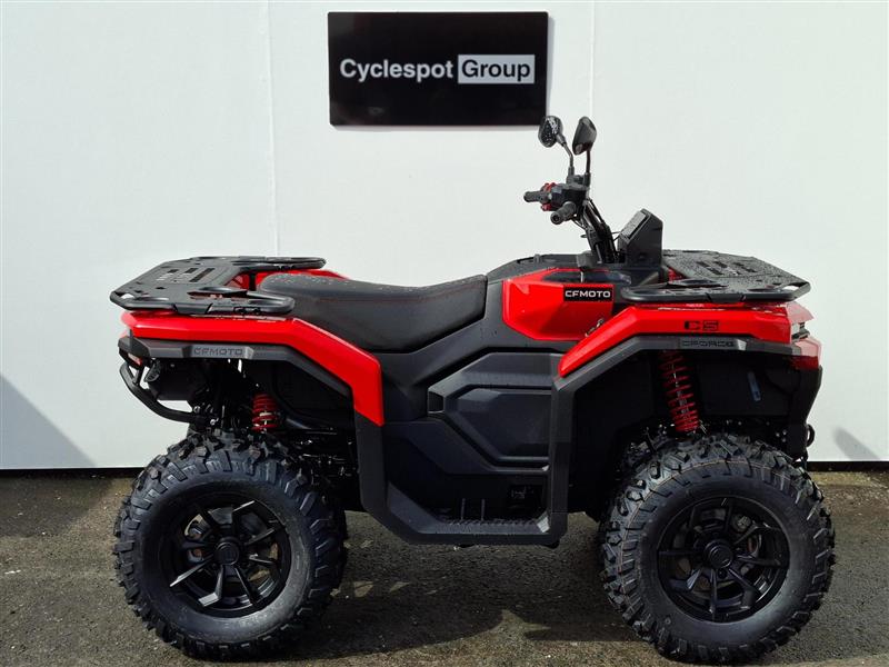 Load image into Gallery viewer, A red and black 2026 CFMOTO CFORCE C5 EPS with large knobby tires, rear cargo racks, and a black seat, photographed in profile against a white wall with a 'Cyclespot Group' sign above it.