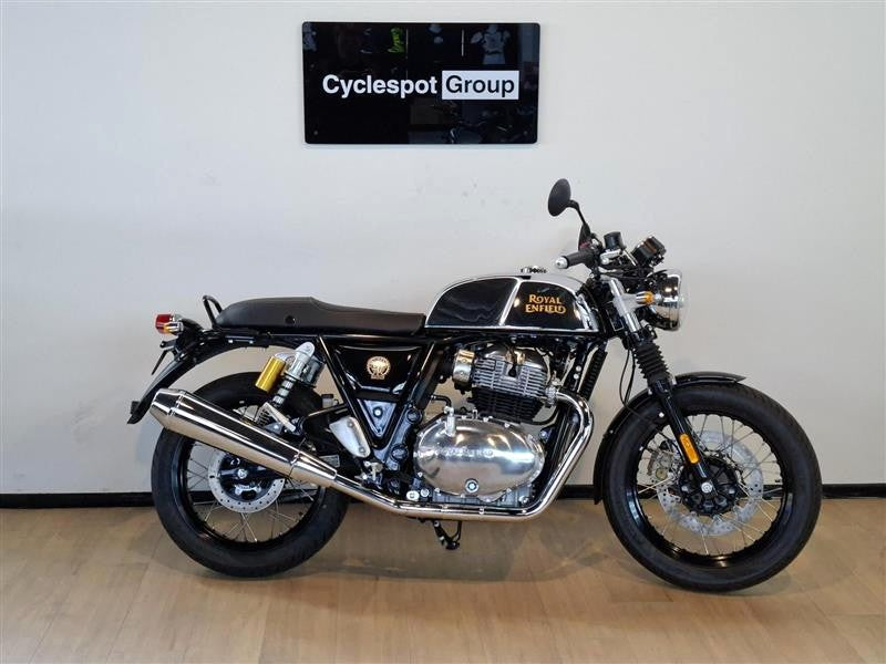 Load image into Gallery viewer, A 2026 Royal Enfield Continental GT Classic Cruiser motorcycle in black and chrome, parked indoors on a light wood floor against a white wall with a 'Cyclespot Group' sign above it.