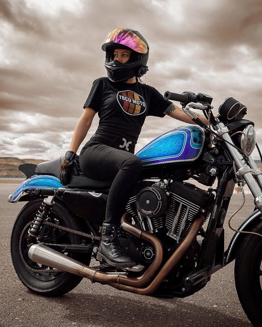 A female rider on a custom motorcycle wearing slim-fit protective women’s motorcycle pants. Stylish and tapered for urban riding. Available at Cyclespot Auckland, Taranaki, Wellington, and online nationwide.