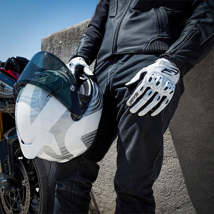Rider wearing white Five Stunt leather motorcycle gloves while holding a white full-face helmet. High-performance summer mesh and leather gloves at Cyclespot Auckland, Taranaki, and Wellington.