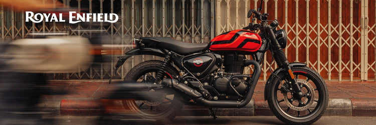 Red Royal Enfield motorcycle parked on a city street with Royal Enfield logo.