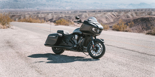 A black 2026 Indian Challenger Limited with saddlebags is parked on a paved desert road with hills and mountains in the background.