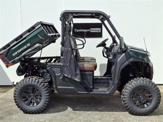 A green 2026 CFMOTO UFORCE U10 PRO side-by-side utility vehicle with its cargo bed raised, parked on a concrete surface against a light gray wall. The vehicle features a dark green and black tonneau cover, a black roll cage, and large off-road tires.