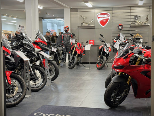 Interior view of the Cyclespot Wellington showroom featuring a line-up of premium Ducati motorcycles, including Multistrada and Panigale models, displayed alongside official riding gear and accessories under bright dealership lighting.