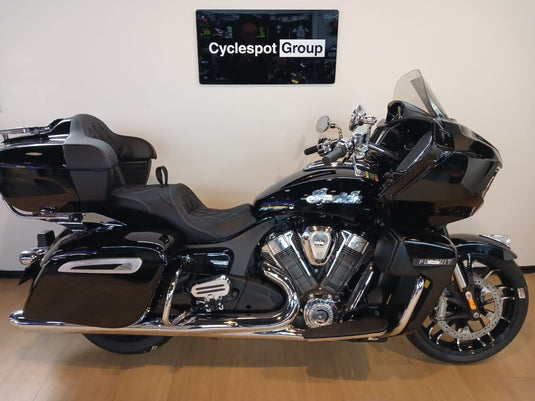 A black Indian Indian Pursuit Limited with 112 Package Motorcycle touring bike with chrome accents, displayed indoors on a wooden floor against a beige wall with a 'Cyclespot Group' sign above.