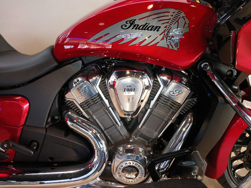 Load image into Gallery viewer, Close-up of a red Indian motorcycle showing the fuel tank decal, chrome V-twin engine, exhaust pipes, and part of the black seat.
