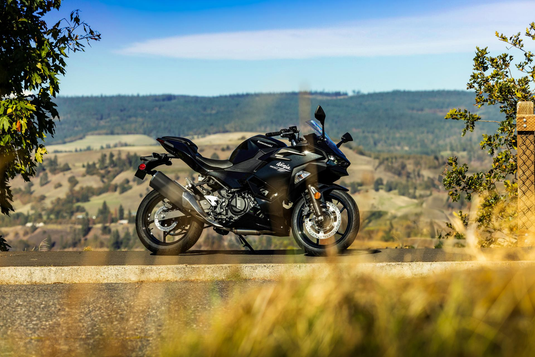 Black Kawasaki Ninja 500 motorcycle on a scenic road with mountains in the background