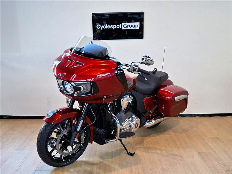 Load image into Gallery viewer, A red and black Indian Challenger Ltd touring motorcycle is parked indoors on a light wood floor against a white wall, with a sign reading 'Cyclespot Group' above it.
