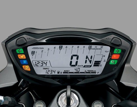 Close-up of a motorcycle digital instrument cluster display on a dark dashboard, showing speed, time, battery, and indicator lights.