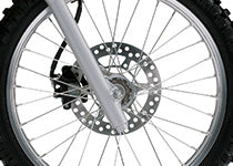 Load image into Gallery viewer, Close-up of a motorcycle or dirt bike front wheel featuring a silver metallic disc brake, multi-spoke wheel, and part of the tire.
