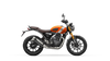 A side profile view of a Triumph Scrambler 400 motorcycle on a solid white background. The motorcycle features a vibrant orange fuel tank, a brown leather seat, black wheels, and silver metallic engine components.